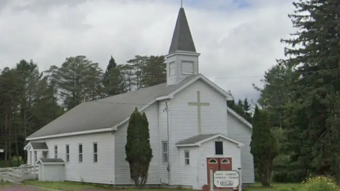 A white building with large cross and steeple.